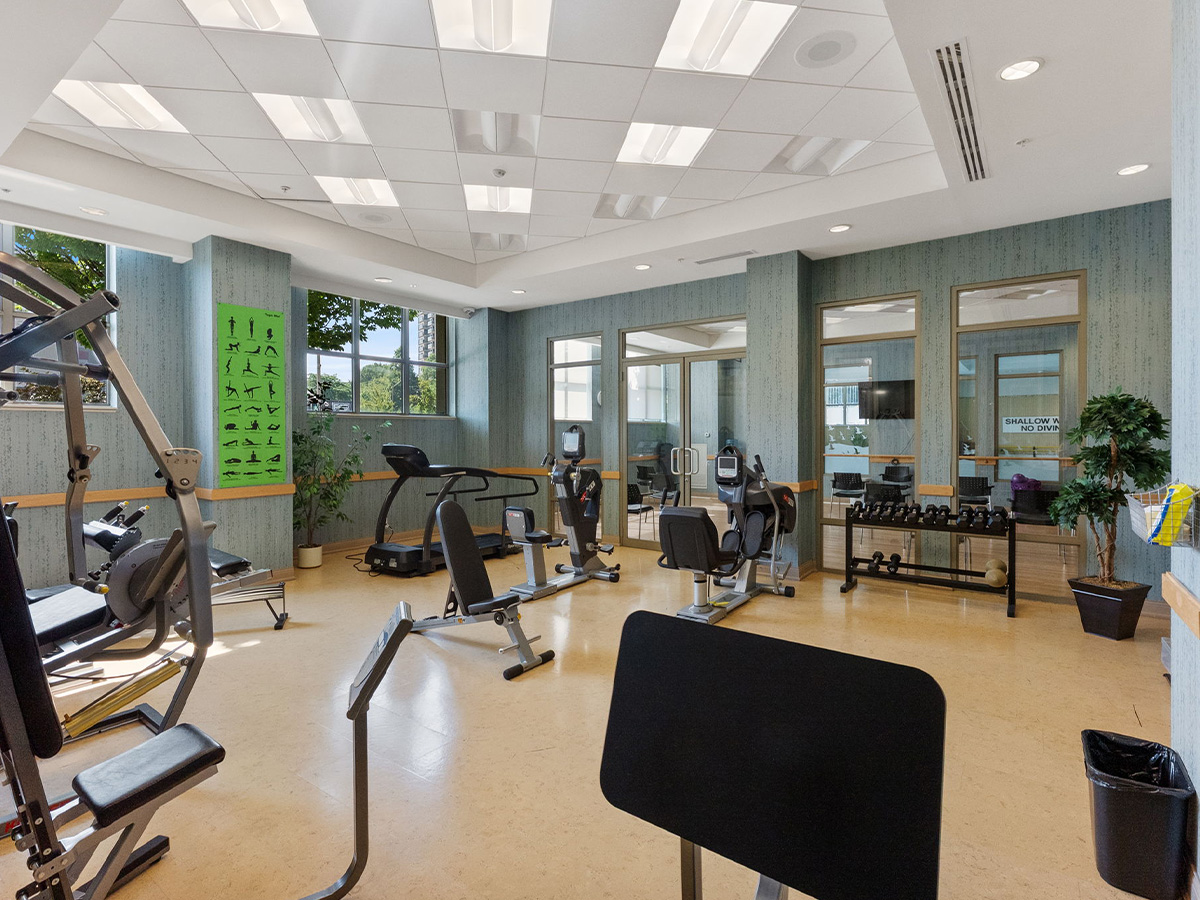 Gym room at Walden Circle Retirement Home featuring exercise equipment and a large window for natural light.