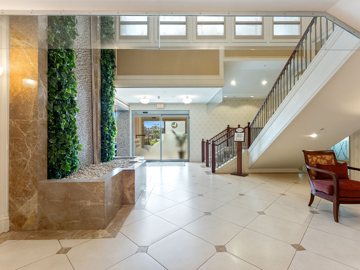 Walden Circle Retirement Home hall lobby with a staircase and a wall beautifully decorated with various plants.