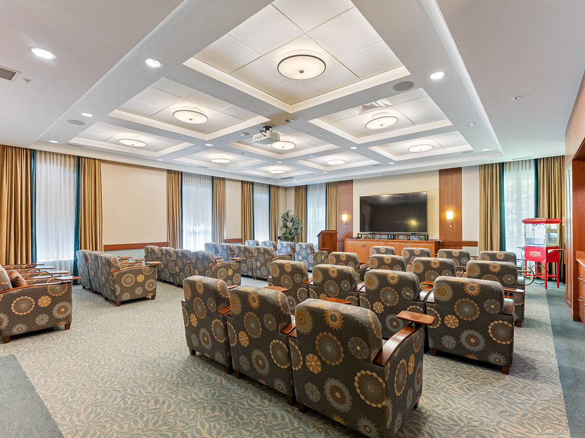 A spacious room at Walden Circle Retirement Home theatre, featuring rows of chairs and a large television screen.