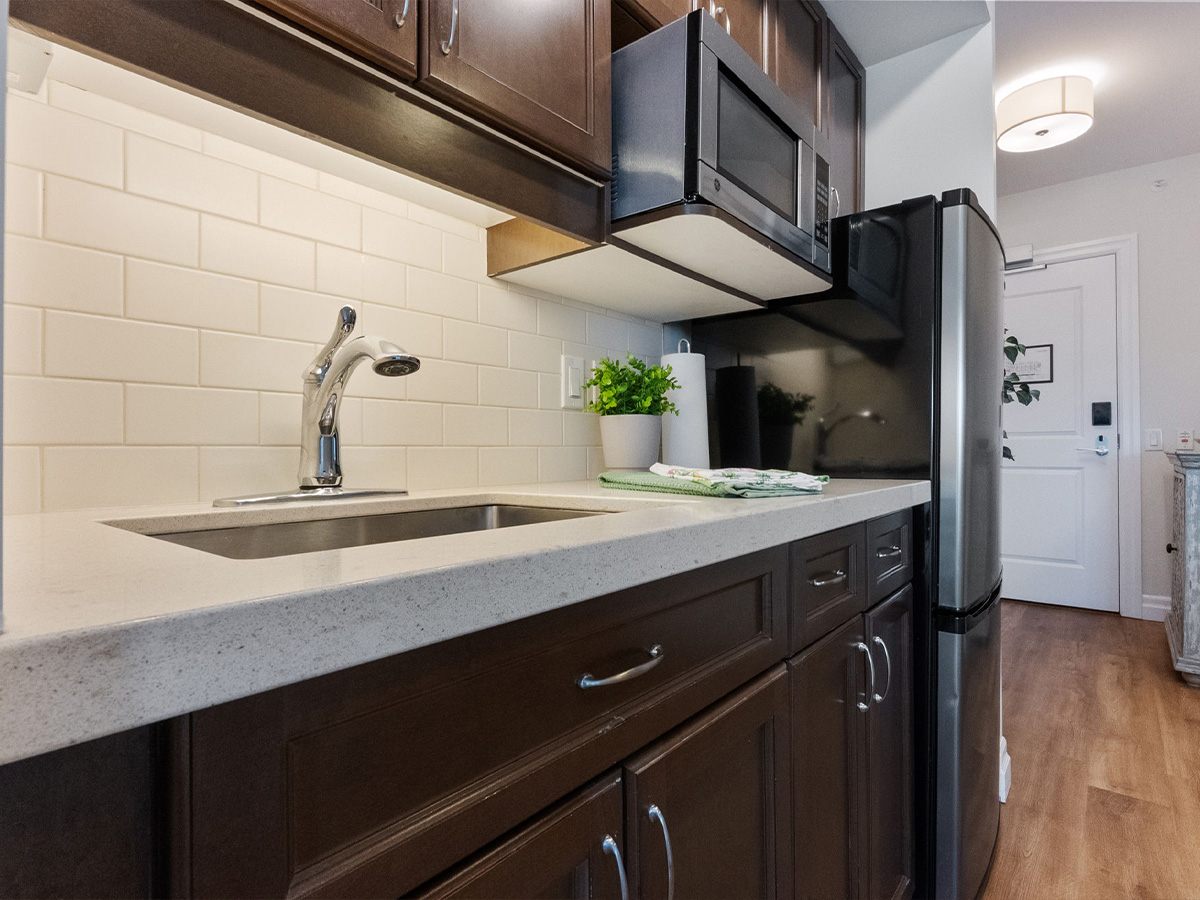 Kitchen at Walden Circle Retirement Home featuring a sink, microwave, and refrigerator.