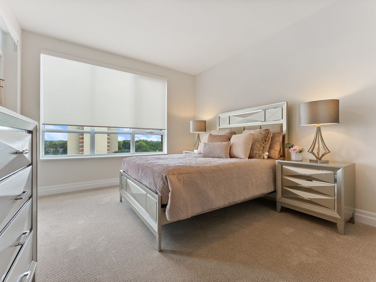 A cozy bedroom at Walden Circle Retirement Home featuring a bed, dresser, and a window letting in natural light.