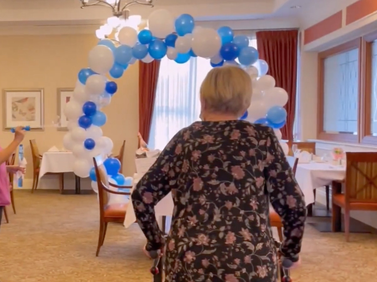 A woman walks through a room filled with colorful balloons at Walden Circle Retirement Home.